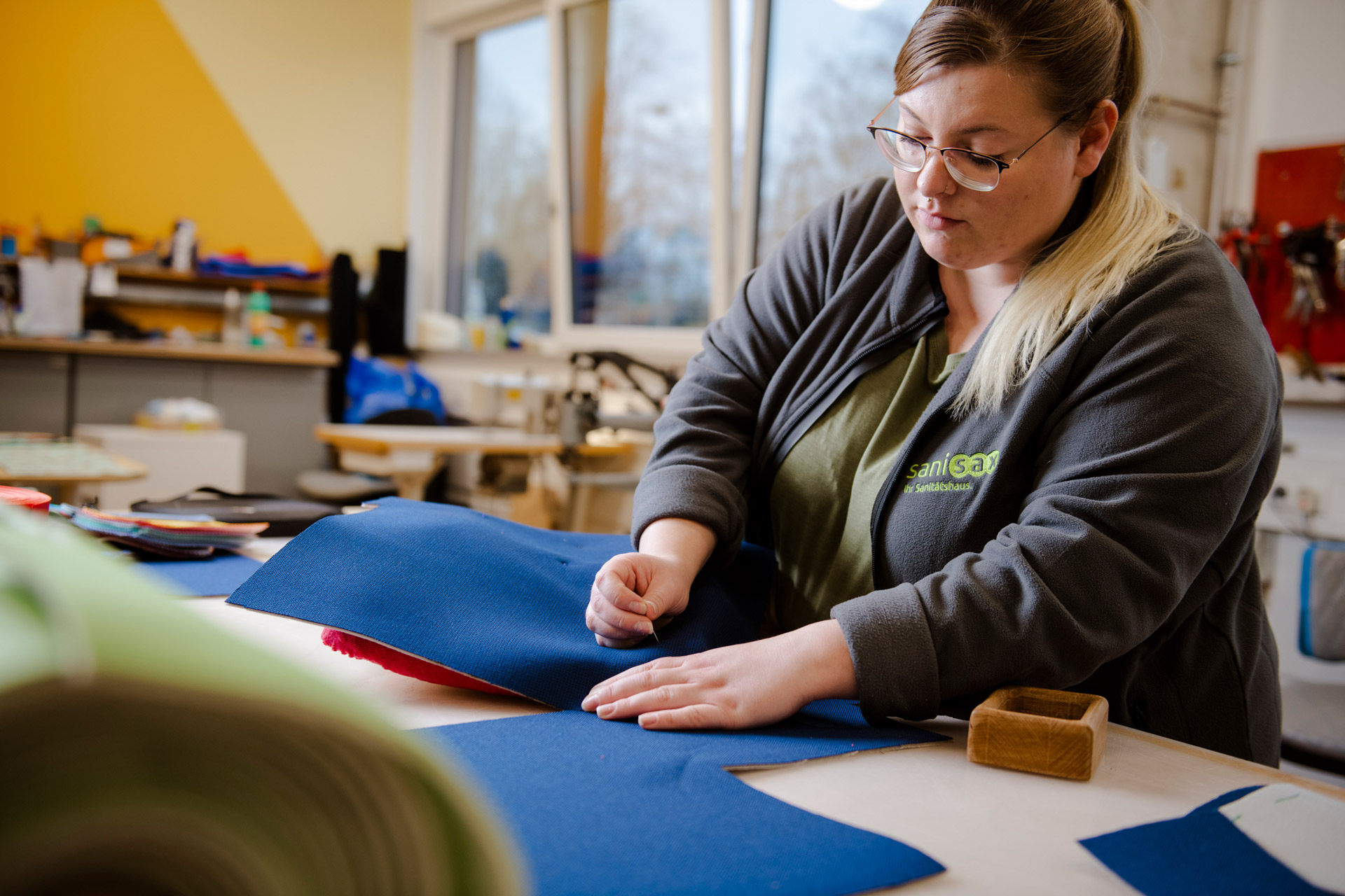 Eine Frau arbeitet professionell an einem Schreibtisch und verarbeitet geschickt vorgeschnittene Stoffe.