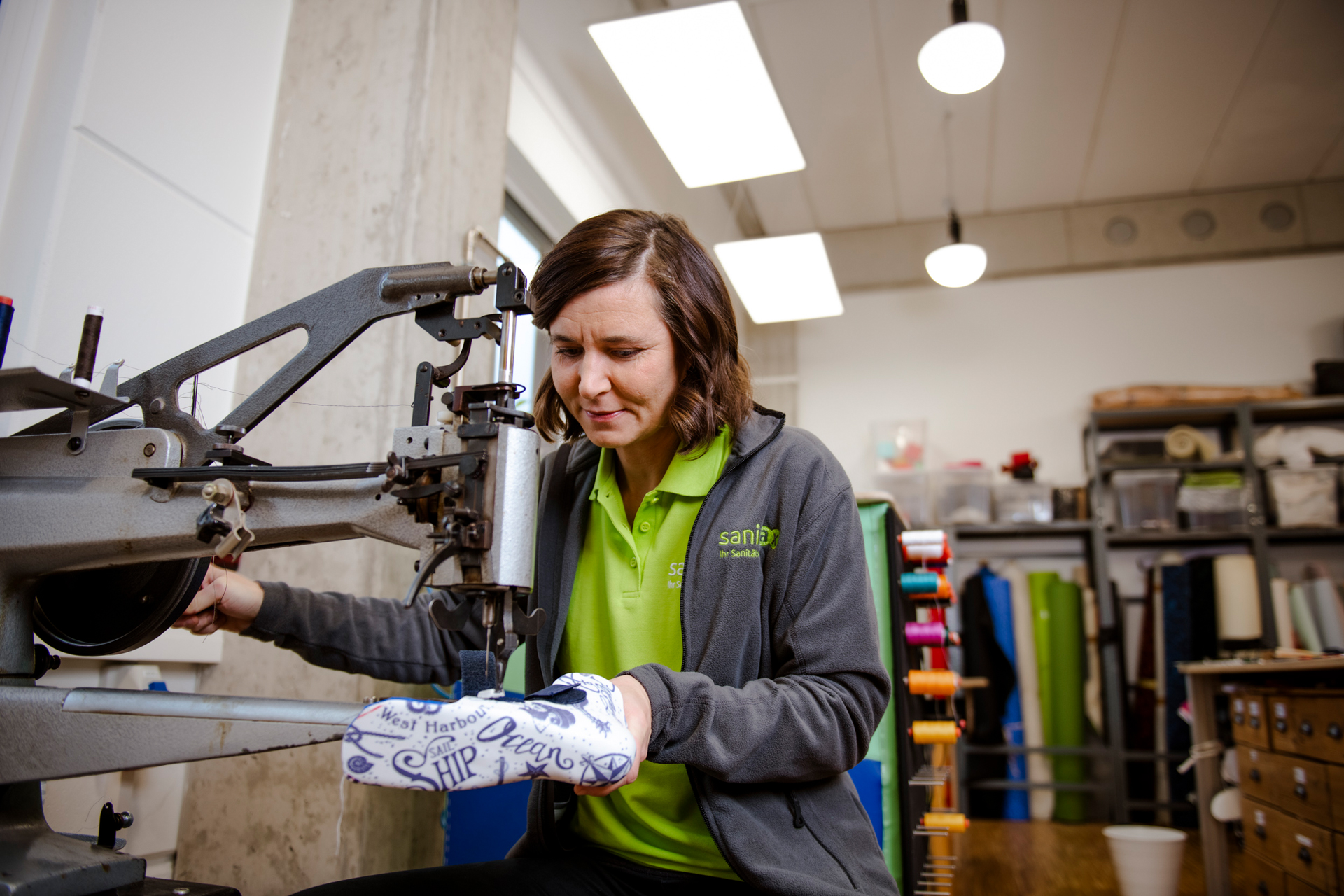 Eine Frau arbeitet an einer Industrienähmaschine und fertigt präzise eine Schuhorthese.